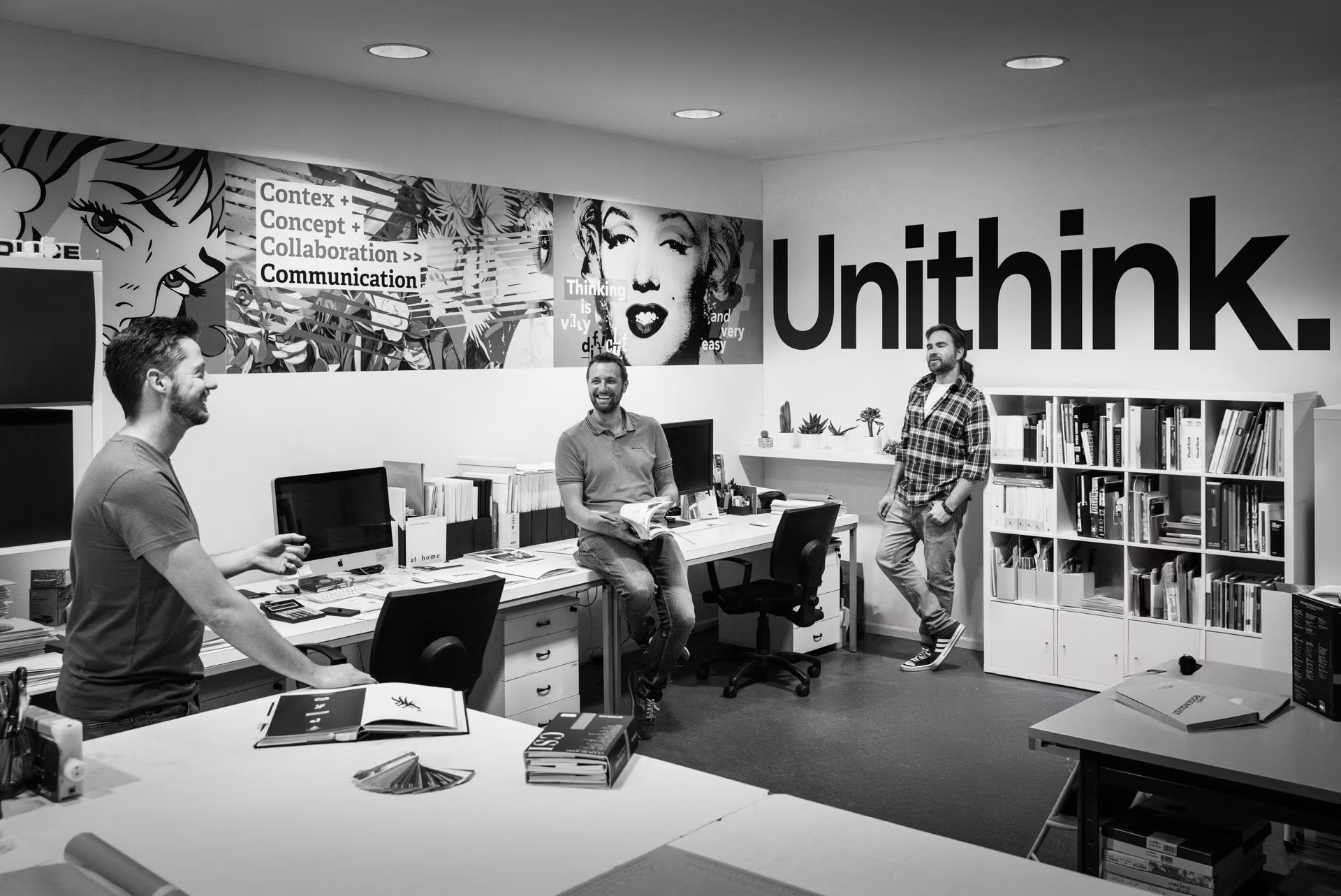 Unithink team in the studio, surrounded by graphic artworks and the Unithink logo wall
